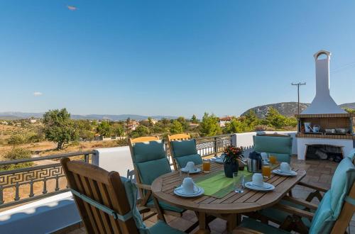 a wooden table and chairs on a balcony with a fireplace at HOUSE NEXT TO THE SEA in Ermioni