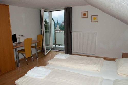 a bedroom with two beds and a table and a balcony at Waldgasthaus in Hochburg