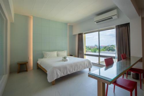 een slaapkamer met een bed, een glazen tafel en een raam bij โรงแรมโกลว์ รัตนา เพลส in Songkhla