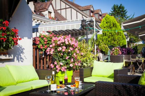 an outdoor patio with green furniture and flowers at Logis Le Bourguignon in Bèze