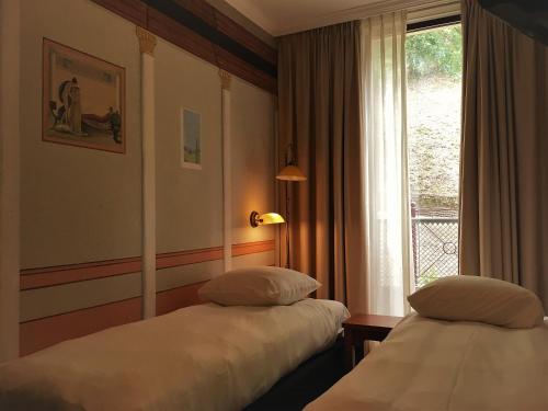 Hotel Courage Waalkade في نايميخن: سريرين في غرفة الفندق مع نافذة
