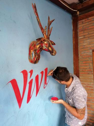 a woman standing next to a wall with a moose head at Arjuna Garden Homestay in Yogyakarta