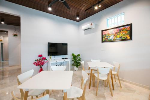 a dining room with white tables and chairs and a flat screen tv at Canning 33 in Ipoh
