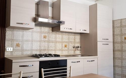 a kitchen with white cabinets and a stove top oven at Stella alpina in Schilpario