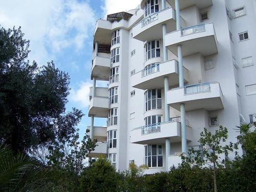 um edifício de apartamentos branco com varandas em Ramat Poleg, walk to beach em Netanya