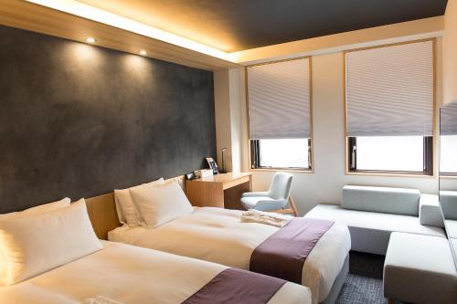 a hotel room with two beds and a chair at Miru Kyoto Nishiki in Kyoto