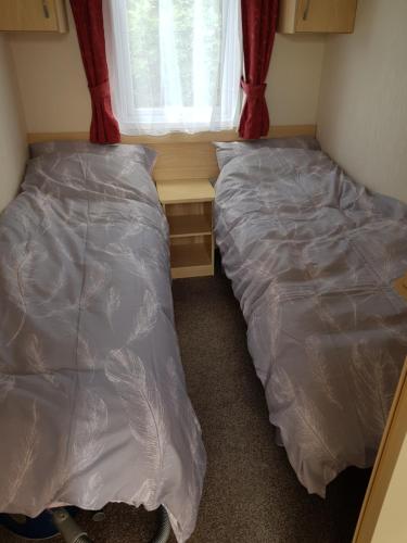 2 łóżka w małym pokoju z oknem w obiekcie Caravan Willerby Gold Star w Looe