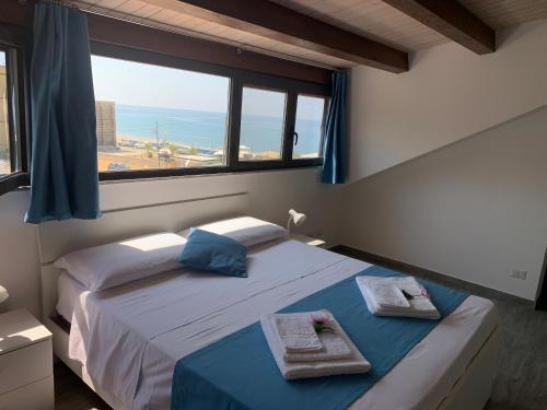 - une chambre avec 2 lits et une grande fenêtre dans l'établissement Le Terrazze in Villa, à Reitano