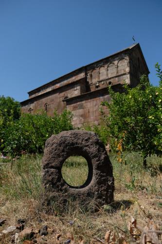 a large rock sitting in the grass in front of a building at Seva Guesthouse and Cottages Byurakan in Byurakan