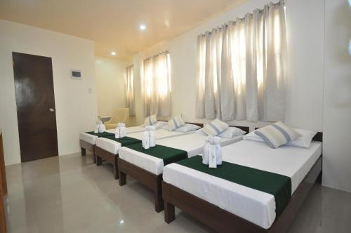 Un grupo de 4 camas en una habitación en RNR Suites, en Legazpi