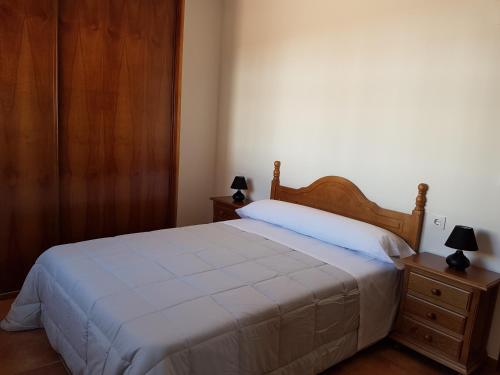um quarto com uma cama branca e duas mesas de cabeceira em Apartamentos Rurales La Dehesa del Acebuche em Jaén