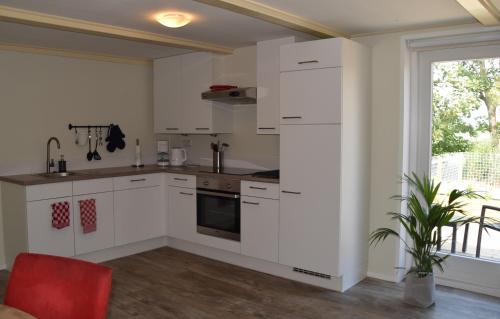 a kitchen with white cabinets and a red chair at Het Friese Landschap in Lemmer