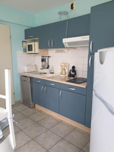 une cuisine avec des armoires bleues et un réfrigérateur blanc dans l'établissement 5 Cours du Maréchal Juin, à Châtelaillon-Plage