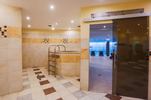 baño con ducha a ras de suelo y puerta de cristal en CE Plaza Hotel, en Siófok