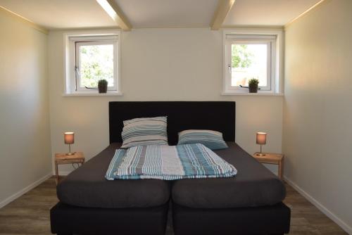 a bed in a room with two windows at Het Friese Landschap in Lemmer