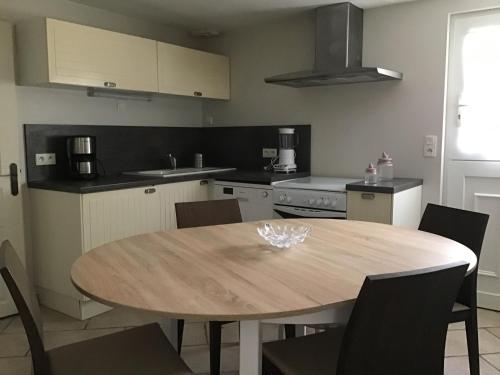 Il comprend une cuisine avec une table et des chaises en bois. dans l'établissement La vallée des pierres, à Saint-Romain-sur-Cher