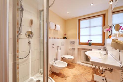 a bathroom with a shower and a toilet and a sink at Romantik Alpenhotel Waxenstein in Grainau