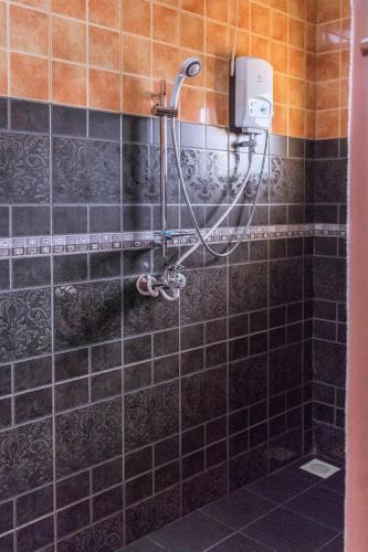 a shower in a bathroom with black tiles at Olina Hotel and Apartments Kampala in Kampala