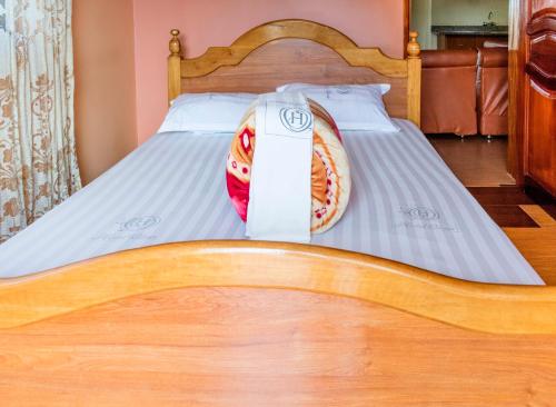 a close up of a bed with a wooden head board at Olina Hotel and Apartments Kampala in Kampala