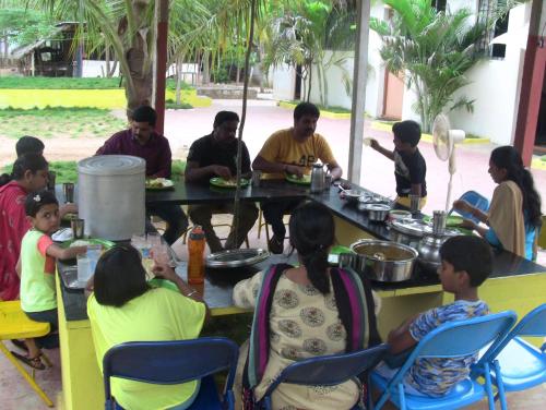 a group of people sitting around a table with food at Holiyday in VGF Farm House in Dānishpet