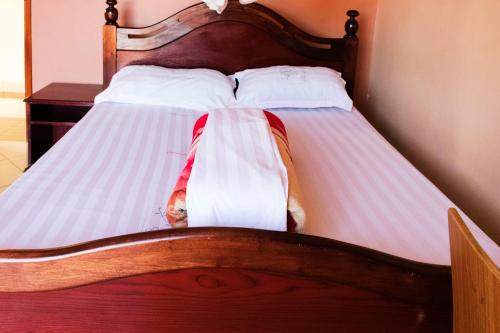 a bed with two pillows and a blanket on it at Olina Hotel and Apartments Kampala in Kampala