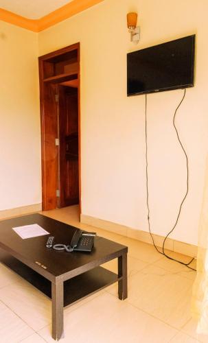 a room with a coffee table and a television on a wall at Olina Hotel and Apartments Kampala in Kampala