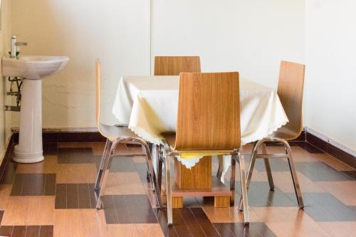 a dining room table with two chairs and a sink at Olina Hotel and Apartments Kampala in Kampala