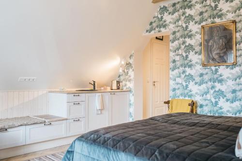 a bedroom with a bed and a kitchen with floral wallpaper at KaksTeist Apartments in Haapsalu