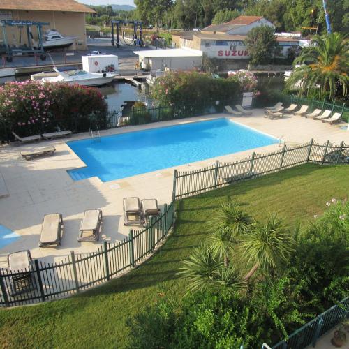 une grande piscine avec des chaises et une cour dans l'établissement Résidence les Grimaudières, à Grimaud