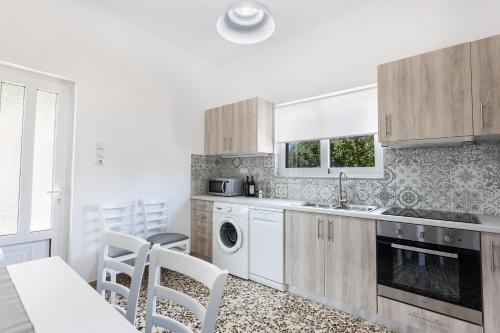 a kitchen with white cabinets and a washer and dryer at Anemelia in Chania