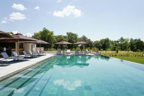 a large swimming pool with chairs and umbrellas at Il Borro Relais & Châteaux in San Giustino Valdarno