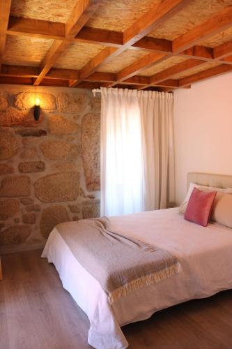a bedroom with a bed and a stone wall at Quinta da Vinha do Souto in Arouca