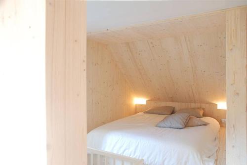 a bedroom with a white bed with two pillows at vakantiehuis met hottub en zicht op de Semois in Herbeumont