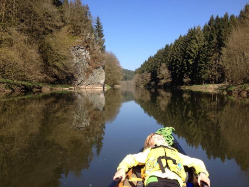 a person is laying in a kayak on a river at vakantiehuis met hottub en zicht op de Semois in Herbeumont
