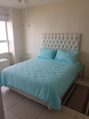 a bedroom with a large bed with blue pillows at Pam's Beach Flat in Amanzimtoti