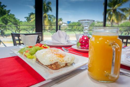 a table with a plate of food and a glass of orange juice at Hotel Costa Brava in Manzanillo