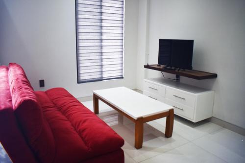 a living room with a red couch and a tv at En el Centro 1 Hermoso Lof't Familiar AC WiFi 300 mbps in Aguascalientes