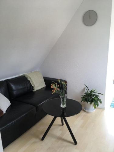 a living room with a black couch and a table at Ro i skoven - men tæt på byen in Varde