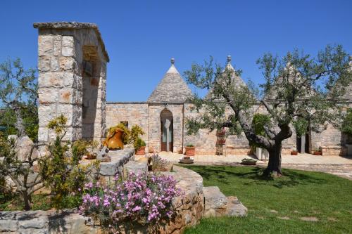 an old stone building with flowers in a yard at Masseria Montanaro in Cisternino