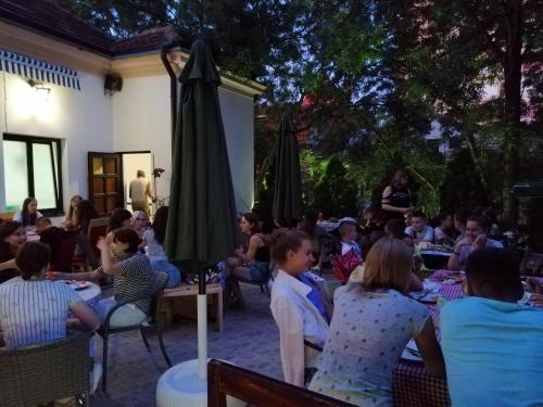 a group of people sitting at tables in a yard at Guest House GOLDEN COIN in Niš