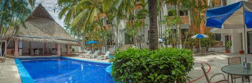 a swimming pool in front of a hotel with palm trees at Hotel Costa Brava in Manzanillo