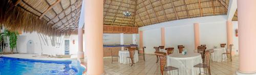 a large room with a pool and tables and chairs at Hotel Costa Brava in Manzanillo