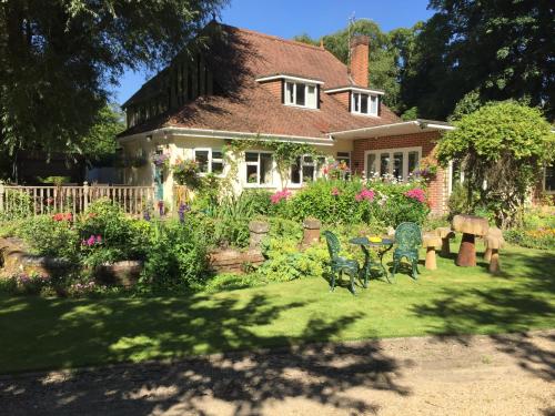 a house with a garden with a table and chairs at Kingswood Cottage in Lyndhurst