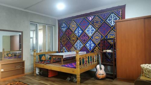 a room with a crib and a wall with a guitar at KGB Home Hostel in Bishkek