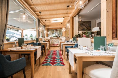 a restaurant with wooden tables and blue chairs at Berghotel - Sexten in Sesto