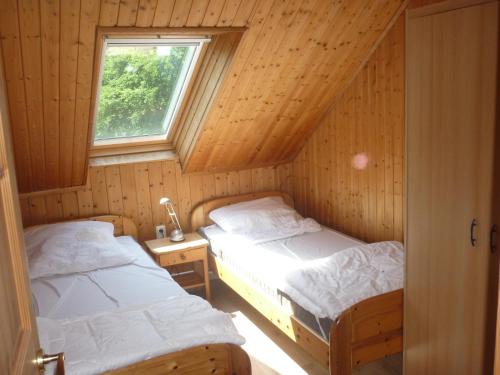 two beds in a wooden room with a window at Ferienhof Gerdes an der Nordsee in Wangerland