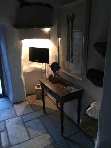 a room with a desk with a television and a bed at Stone house by Anemos in Agios Ioannis
