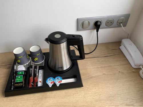 a coffee maker on a black tray on a floor at ATOLON PARK HOTEL in Brumath