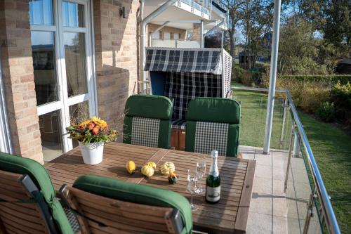 a wooden table with chairs and a bottle of wine at Landhaus am Binnensee in Fehmarn