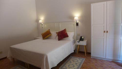 a bedroom with a white bed with two pillows on it at Chiosi Country Club in Corleone
